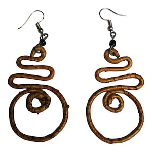 Puede incluir: Un par de pendientes de alambre tejido marrón con ganchos plateados. Los pendientes tienen forma de círculo con un círculo más pequeño en el interior. Los pendientes miden aproximadamente 5 cm de largo.