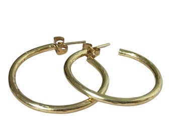May include: A pair of gold hoop earrings with a hammered texture. The earrings are simple and elegant.