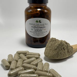 Peut inclure: Un flacon en verre ambr&eacute; avec un bouchon noir &eacute;tiquet&eacute; Herbal Cell Food Plus Crafted Organics, contenant des g&eacute;lules brunes. Une cuill&egrave;re en bois contient un tas de poudre brun clair, et plusieurs g&eacute;lules identiques sont &eacute;parpill&eacute;es.