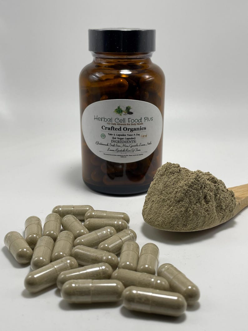 Peut inclure: Un flacon en verre ambr&eacute; avec un bouchon noir &eacute;tiquet&eacute; Herbal Cell Food Plus Crafted Organics, contenant des g&eacute;lules brunes. Une cuill&egrave;re en bois contient un tas de poudre brun clair, et plusieurs g&eacute;lules identiques sont &eacute;parpill&eacute;es.