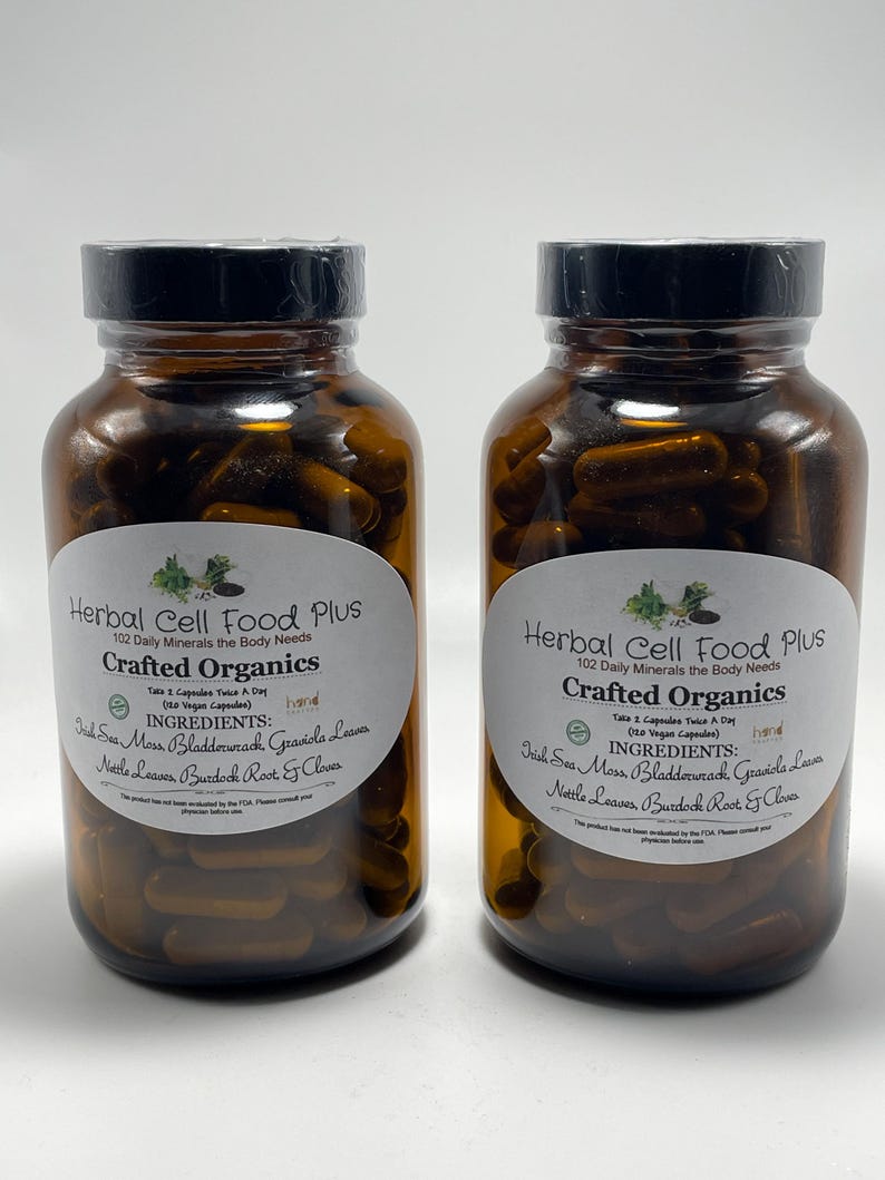 Peut inclure: Deux flacons en verre ambr&eacute; remplis de g&eacute;lules brun fonc&eacute;, chacun avec une &eacute;tiquette blanche indiquant Herbal Cell Food Plus, Crafted Organics, et listant des ingr&eacute;dients comme Irish Sea Moss, Bladderwrack, Graviola Leaves, Nettle Leaves, Burdock Root et Cloves.