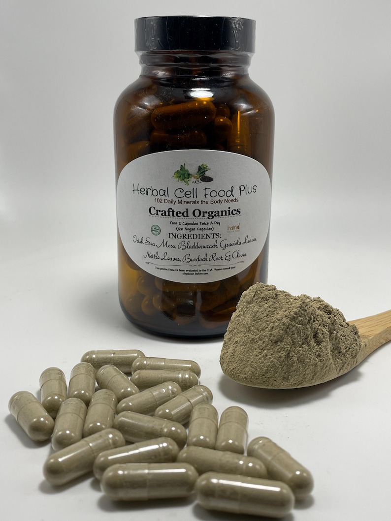 Peut inclure: Un flacon en verre brun &eacute;tiquet&eacute; Herbal Cell Food Plus contenant des g&eacute;lules, avec une cuill&egrave;re en bois contenant un tas de poudre brun clair et plusieurs g&eacute;lules &eacute;parpill&eacute;es devant, le tout pr&eacute;sentant un aspect brun clair et terreux.