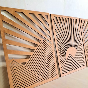 Op de afbeelding: Drie houten wanddecoratiepanelen met een geometrisch berg- en zonontwerp. De panelen zijn gemaakt van lichtbruin hout en hebben een uitgesneden ontwerp.