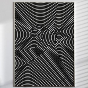 以下が含まれることがあります： 黒い背景に白い線画でヘ音記号の形が描かれた長方形のウォールアートプリント。このアートワークは細い金属製のフレームに収められており、同心円状に流れる一連の線が描かれています。
