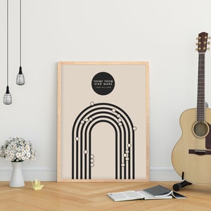 May include: A framed poster with the text "THEME FROM STAR WARS" and a black and white graphic design. An acoustic guitar stands to the right. A white vase with white flowers and a book are on the wooden floor.
