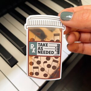 May include: A sticker of a brown pill bottle with a white lid and the text "TAKE AS NEEDED" on the label. The bottle is filled with musical notes.