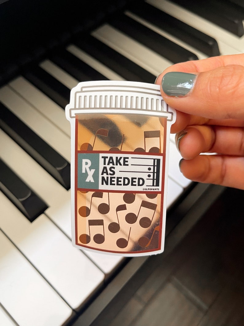 May include: A sticker of a brown pill bottle with a white lid and the text "TAKE AS NEEDED" on the label. The bottle is filled with musical notes.