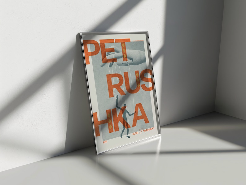 May include: A framed poster with the text "PETRUS HKA" in orange letters on a blue background. A hand with strings attached to it is holding a small figure in the centre of the poster. The text "IGOR "TRAVINSKY" is at the bottom of the poster.