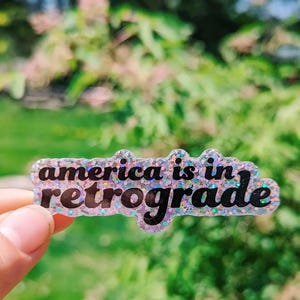 Adesivo in vinile GLITTER "America è in fase retrograda"