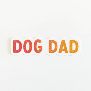 May include: White sticker with the words "DOG DAD" in red and orange lettering.