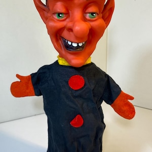 May include: A white ceramic mug with a black handle and the text "But First, Coffee" in a black, handwritten-style font. The mug is on a white surface.