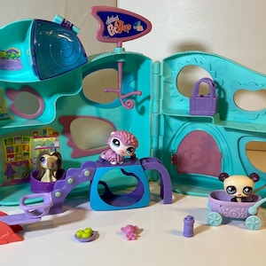 May include: A colorful Pet Shop playset with multiple levels, featuring various animal figurines and accessories. The playset is primarily teal and purple, with a sign that reads "Littlest Pet Shop". Includes a seesaw, a swing set, and a small stroller.