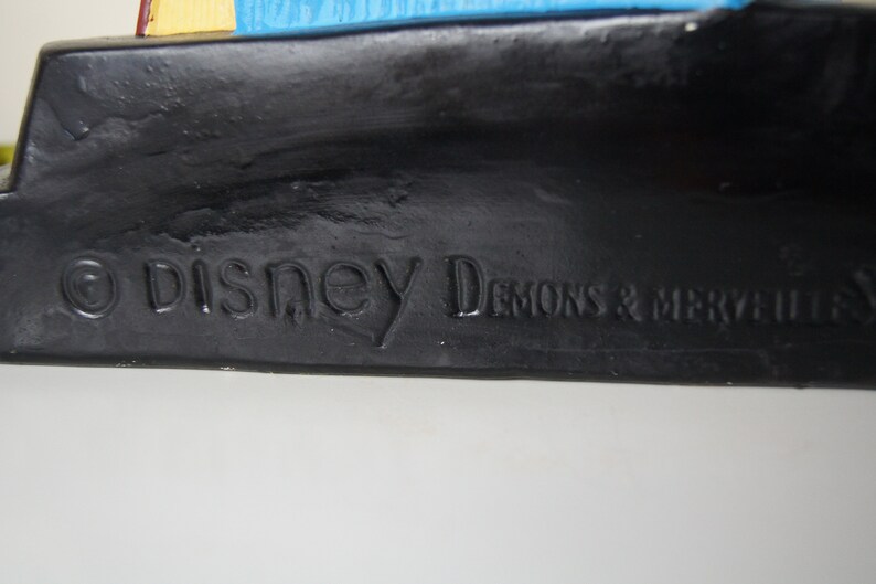 May include: Close-up of a black base with the text "&copy; Disney Demons & Merveilles" embossed on it.