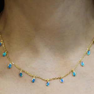 May include: A gold chain necklace with multiple teardrop-shaped blue opal pendants.