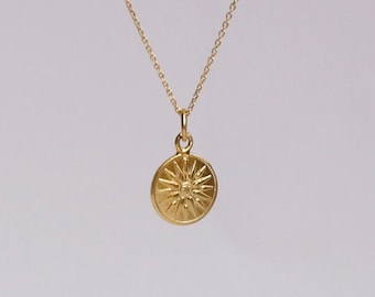 Peut inclure: Un collier en chaîne dorée avec un petit pendentif rond orné d'un motif soleil.