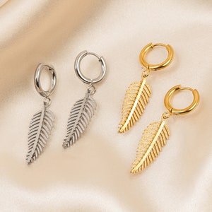 Könnte beinhalten: Zwei Paar Ohrringe mit einem Federdesign. Ein Paar ist golden und das andere ist silber.