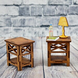 May include: Two wooden end tables with a shelf, one with a lamp and a bottle of water on top, and a book on the shelf. The tables are on a wood floor in front of a brick wall.