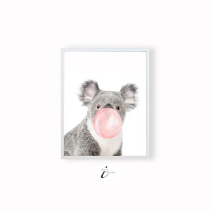 K&ouml;nnte beinhalten: Ein gerahmter Druck mit einer Aquarellillustration eines Koalas mit einer rosa Kaugummiblase. Der Koala ist grau mit flauschigen Ohren und einer wei&szlig;en Brust. Der Druck ist in einem wei&szlig;en Rahmen.