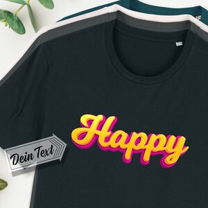 Könnte beinhalten: Schwarzes T-Shirt mit einem gelben und pinken "Happy"-Motiv. Der Text "Dein Text" befindet sich in einem weißen Kasten mit einem Pfeil, der auf das Motiv zeigt.