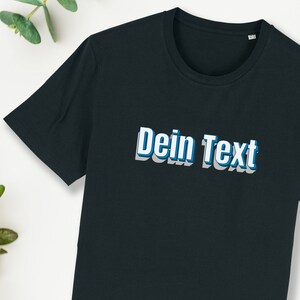 Könnte beinhalten: Ein schwarzes T-Shirt mit dem Text "Dein Text" in Weiß mit blauem Umriss.