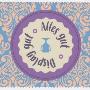 May include: A purple and white circular sticker with a blue silhouette of a scale and the text "Alles gut!  Display gut" in German.