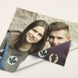 Pode incluir: Um pano de limpeza de microfibra com um design de folhas coloridas. O pano apresenta uma foto de duas pessoas sorrindo para a c&acirc;mera.