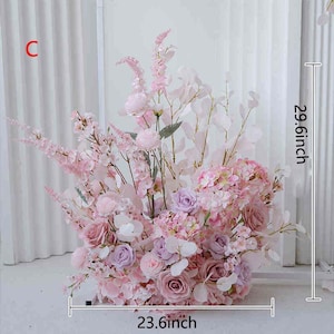 May include: A large floral arrangement featuring a variety of pink and purple flowers, including roses and hydrangeas. The arrangement is 29.6 inches tall and 23.6 inches wide. The flowers are arranged in a dense, full display, perfect for weddings or events.