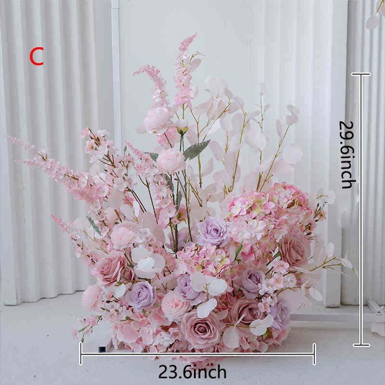 May include: A large floral arrangement featuring a variety of pink and purple flowers, including roses and hydrangeas. The arrangement is 29.6 inches tall and 23.6 inches wide. The flowers are arranged in a dense, full display, perfect for weddings or events.
