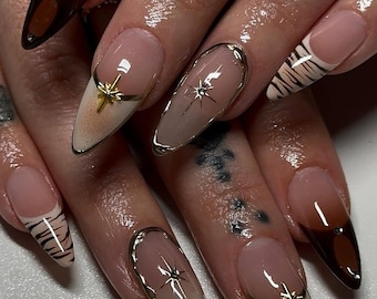 Vernis à presser luxueux marron et or, impression élégante d'étoiles et de zèbres sur de faux ongles, ongles pointes françaises, décoration d'ongles inspirée d'étoiles dorées et de zèbres