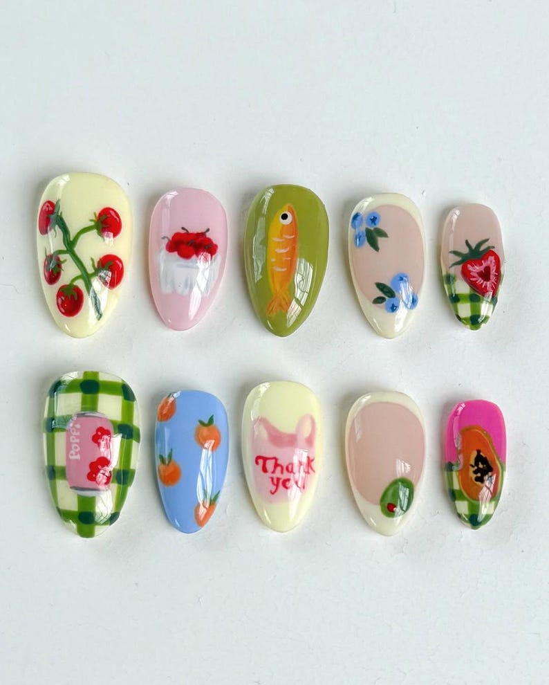 Peut inclure: Ensemble de dix faux ongles avec diff&eacute;rents motifs, dont une plante de tomates, un bol de cerises, un poisson, des myrtilles, une fraise, un motif &agrave; carreaux, des p&ecirc;ches, un message de remerciement, une feuille verte et une papaye.