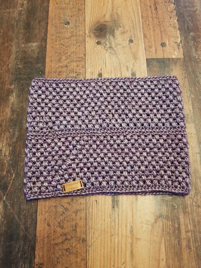 Puede incluir: Calientacuellos de punto de color morado con una etiqueta de cuero marr&oacute;n que dice "Needle Pearl".