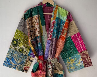 May include: A patchwork robe with a vibrant mix of colors and patterns. The robe features a belt and pockets, and is displayed on a wooden hanger. The design incorporates various fabrics and textures, creating a unique and artistic look.