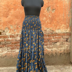 May include: A long, blue skirt with a tiger print. The skirt has a smocked waistband and a tiered design.