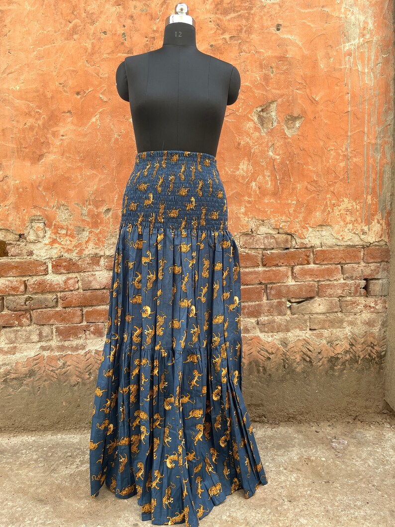 May include: A long, blue skirt with a tiger print. The skirt has a smocked waistband and a tiered design.