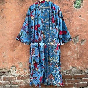 May include: A blue cotton robe with a floral and bird print. The robe has a tie belt and is open in the front. The text "DHANLAXMI HANDICRAFTS" is printed on the bottom of the robe.