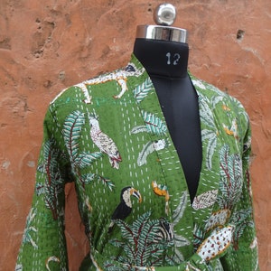 May include: A green cotton robe with a jungle print featuring toucans, zebras, leopards, and flamingos. The robe has a tie belt and long sleeves.