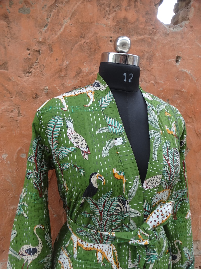 May include: A green cotton robe with a jungle print featuring toucans, zebras, leopards, and flamingos. The robe has a tie belt and long sleeves.