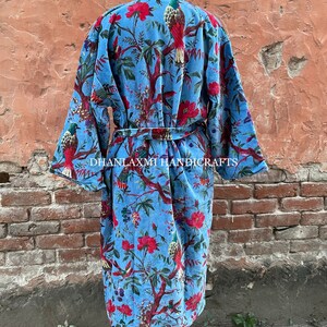May include: A blue cotton robe with a floral and bird print. The robe has a tie belt and long sleeves. The text "DHANLAXMI HANDICRAFTS" is printed on the robe.