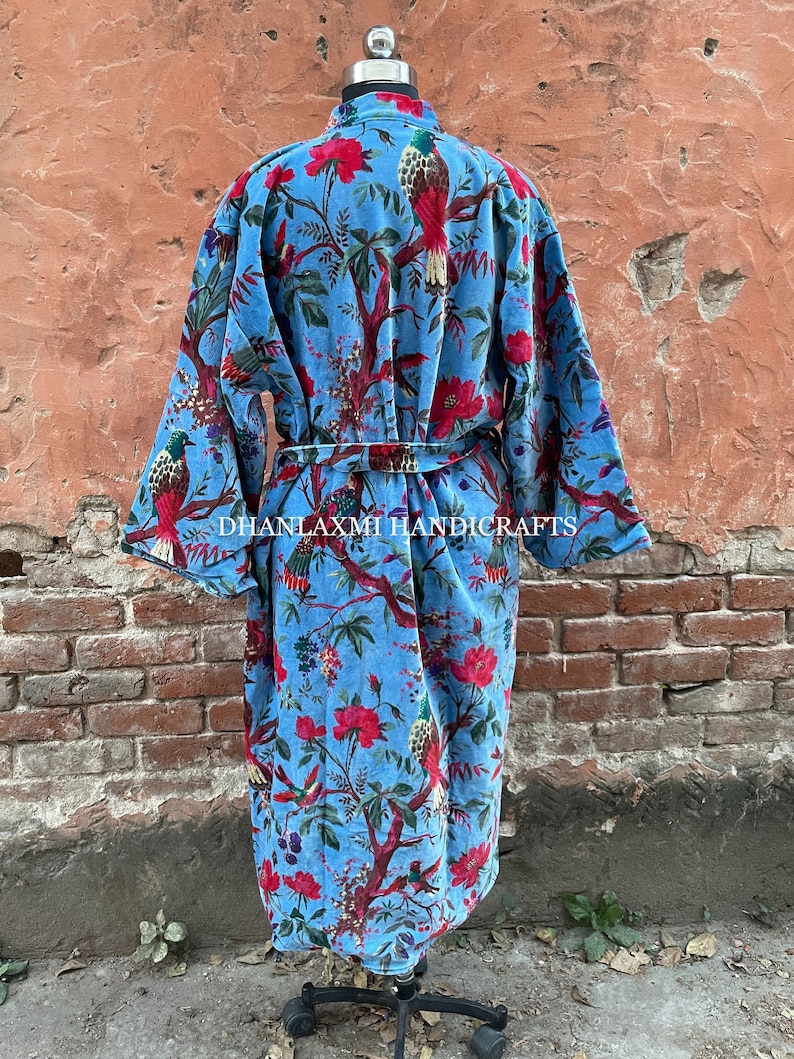 May include: A blue cotton robe with a floral and bird print. The robe has a tie belt and long sleeves. The text "DHANLAXMI HANDICRAFTS" is printed on the robe.