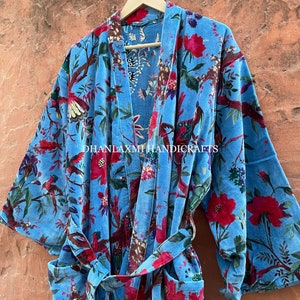 May include: A blue cotton robe with a floral print featuring red flowers, green leaves, and birds. The robe has a tie belt and long sleeves. The text "DHANLAXMI HANDICRAFTS" is printed on the robe.