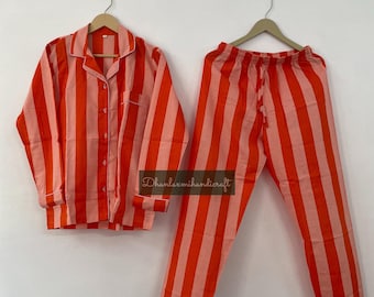 May include: A striped pajama set with a long-sleeved shirt and pants. The shirt has a button-up front and the pants have a drawstring waist. The pajamas are pink and orange with vertical stripes.