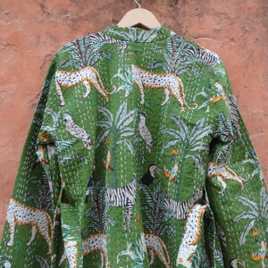May include: A green cotton robe with a jungle print featuring zebras, leopards, toucans, and palm trees. The robe has a long sleeve and a tie belt.