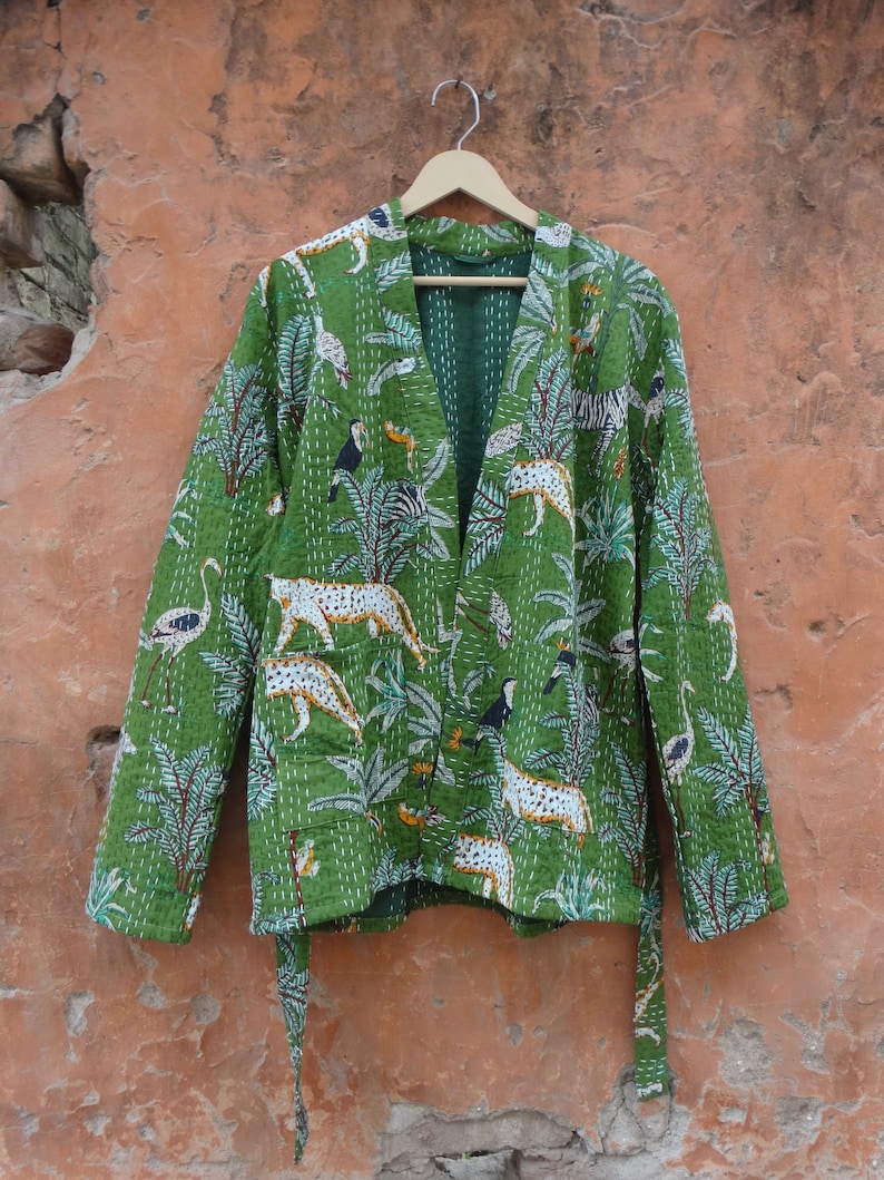 May include: A green quilted jacket with a belt and a jungle print featuring leopards, toucans, and palm trees.
