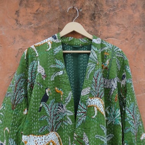 May include: A green kantha quilted jacket with a jungle print featuring zebras, toucans, and leopards. The jacket has a V-neck and a long, open front.