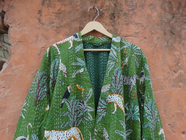 May include: A green kantha quilted jacket with a jungle print featuring zebras, toucans, and leopards. The jacket has a V-neck and a long, open front.