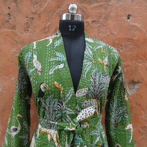 May include: A green cotton jacket with a floral and animal print. The jacket has a long sleeve and a tie belt. The print features toucans, zebras, and flamingos.