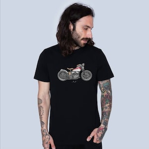 Puede incluir: Camiseta negra con un gráfico de motocicleta vintage impreso en la parte delantera. La motocicleta es gris y blanca con detalles rojos.