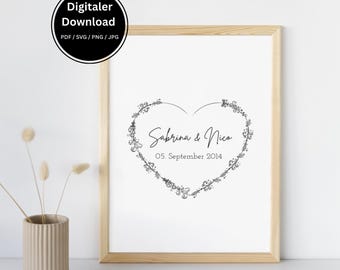 May include: A framed print with a light wood frame. The print features a heart-shaped floral design with the names "Sabrina & Nico" and the date "05. September 2014". The top left corner has a black circle with the text "Digitaler Download".