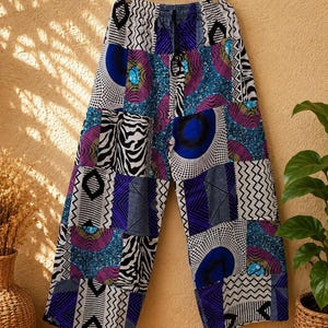 May include: Wide-leg pants featuring a patchwork design with various patterns including zebra stripes, blue and purple circles, and geometric zig-zag lines. The pants have an elastic waistband with a black drawstring and a loose, flowing fit.