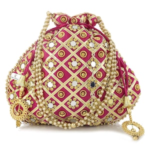 May include: A magenta drawstring pouch with gold and mirror embellishments. The bag features a geometric pattern with gold trim and small mirrors. White beaded accents and gold tassels add to the ornate design. The bag is likely used for carrying small items.
